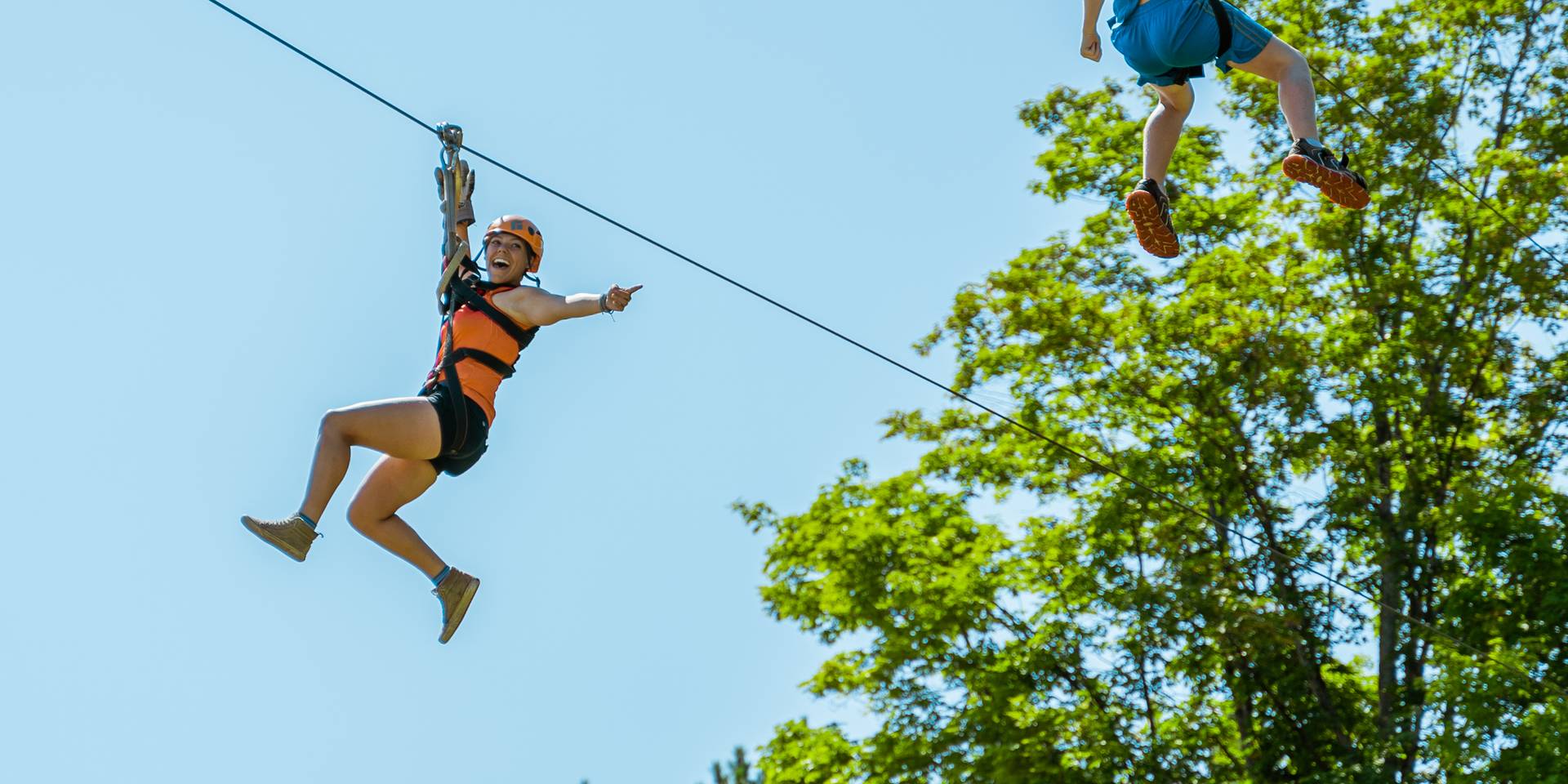 Two people ziplining through the air in the summer