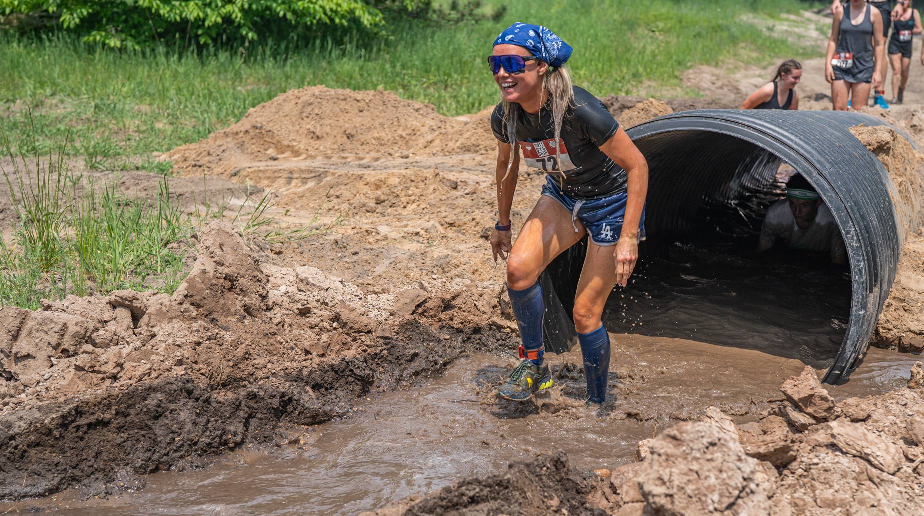 Girl coming out of large tube in the mud