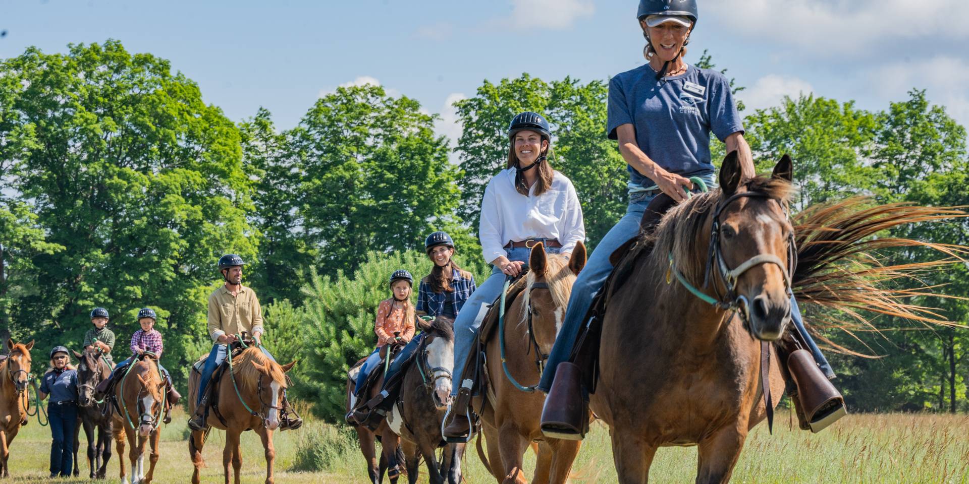 Horse wrangler leading group on trail ride
