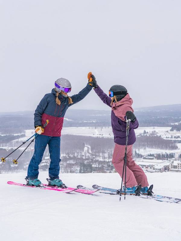 Two skiers at the top of the mountain high fiving