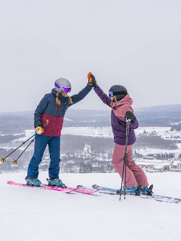 Two skiers at the top of the mountain high fiving