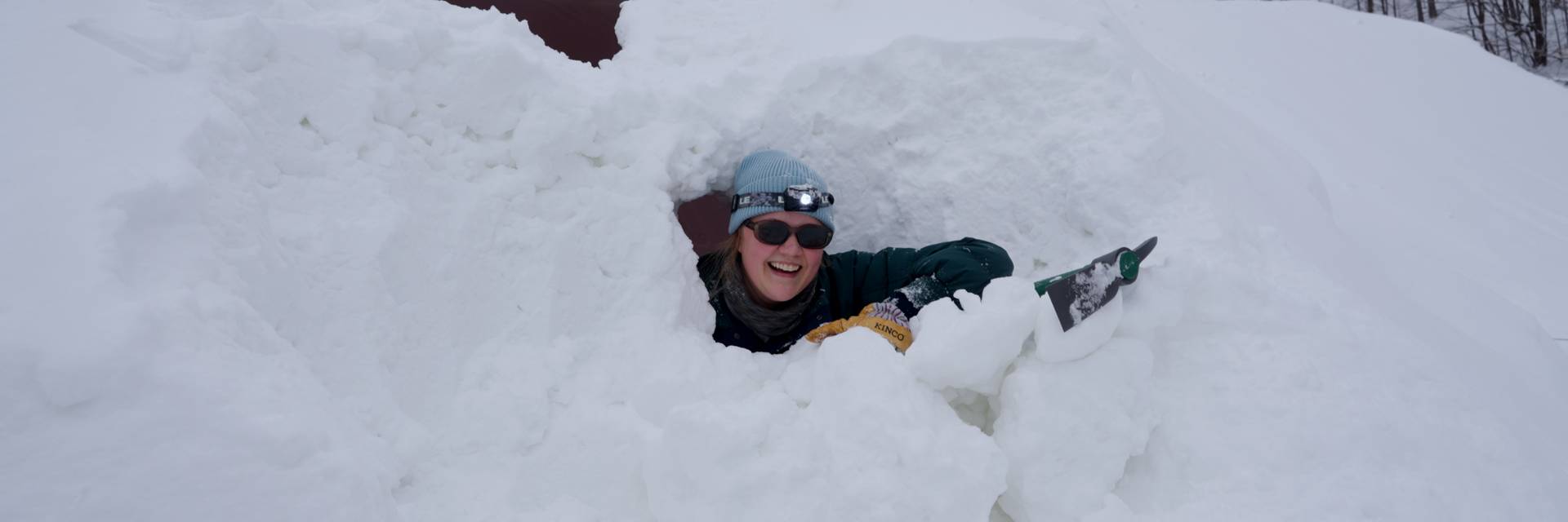 Woman poking head of of a snow mound