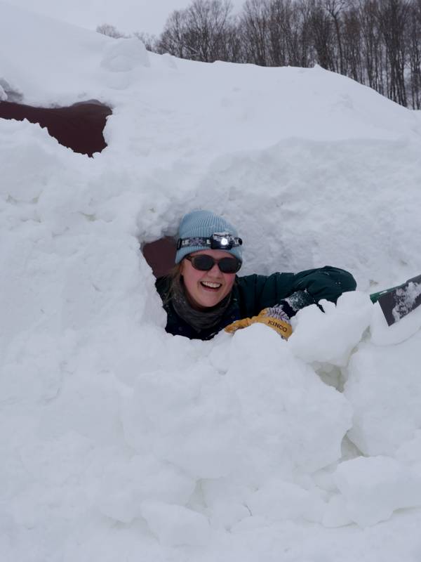 Woman poking head of of a snow mound
