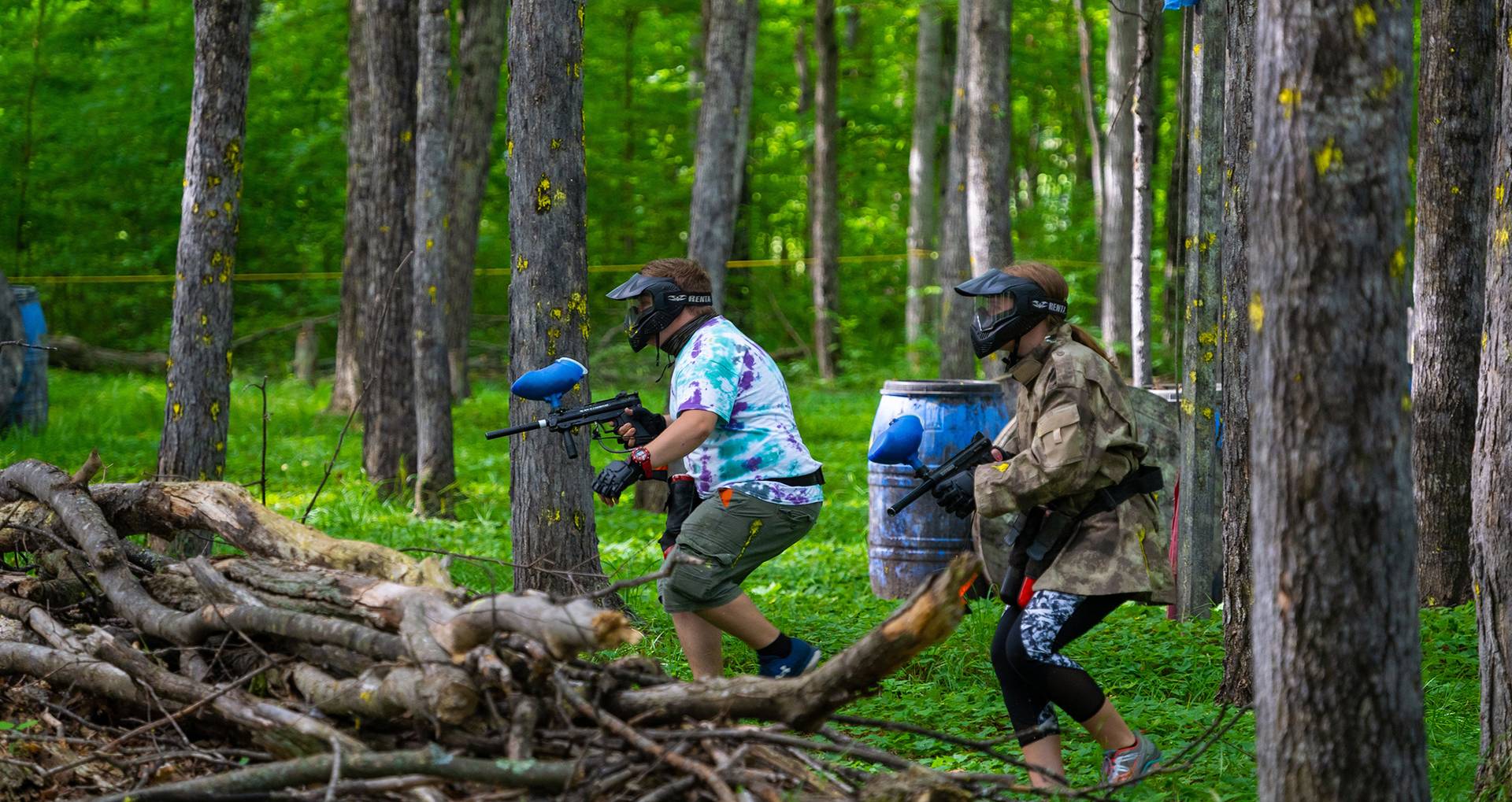 Two men in on the hunt for opponents with paintball guns.