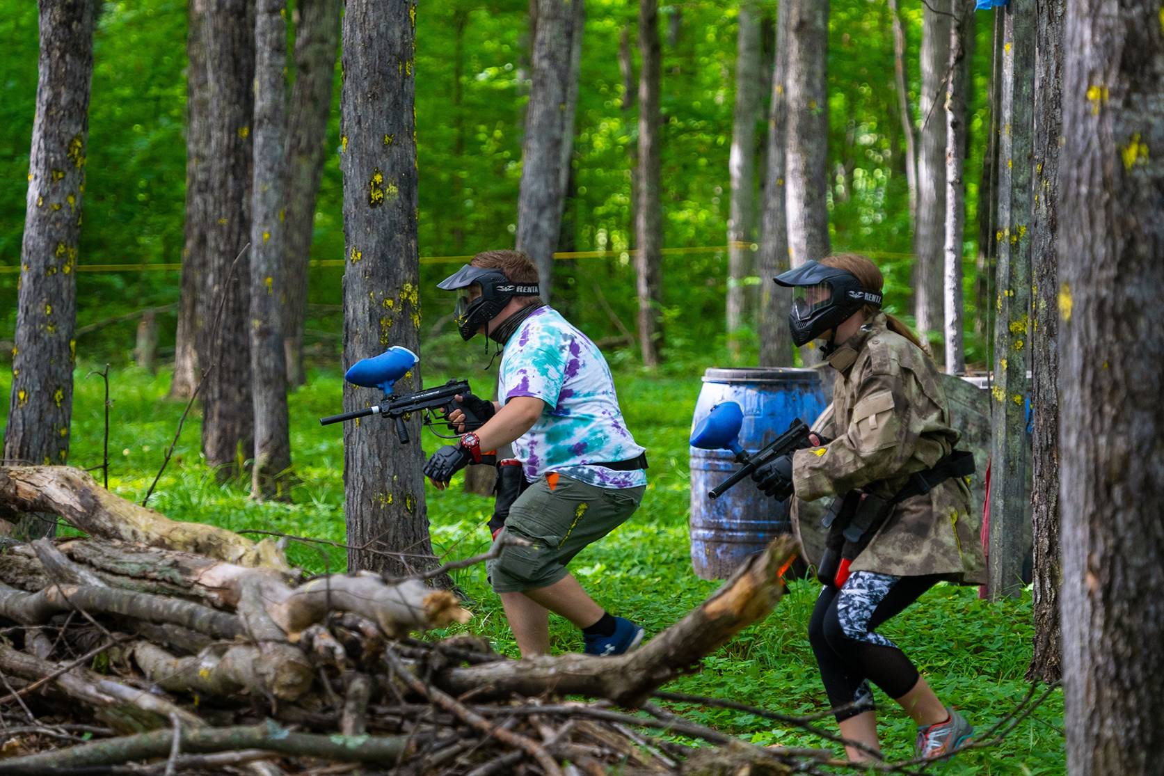 Two men in on the hunt for opponents with paintball guns.