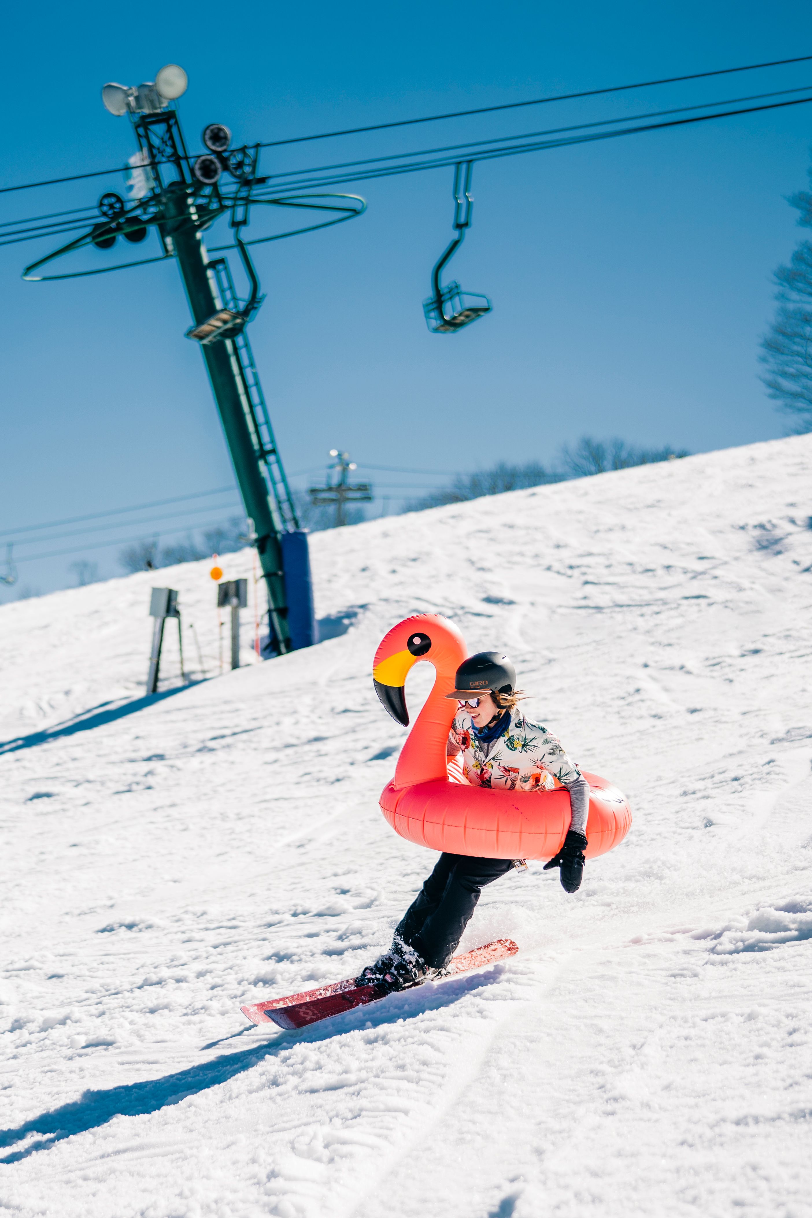 Guy skiing with flamingo tube around him