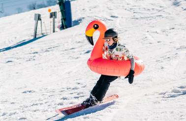 Guy skiing with flamingo tube around him
