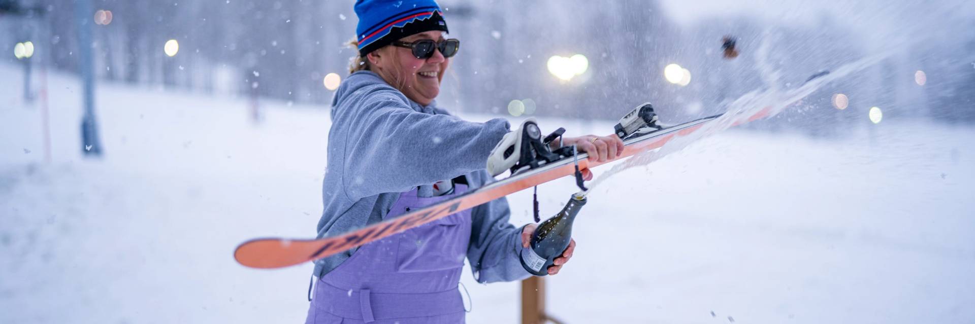 Woman opening a bottle of champagne with a ski