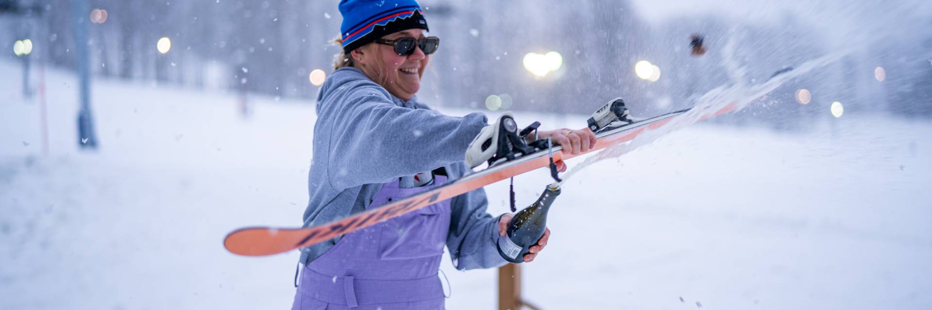 Woman opening a bottle of champagne with a ski