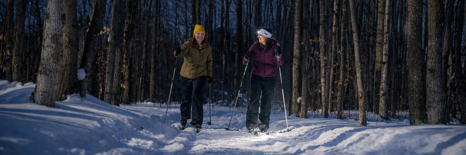 Two women cross country skiing in the sun