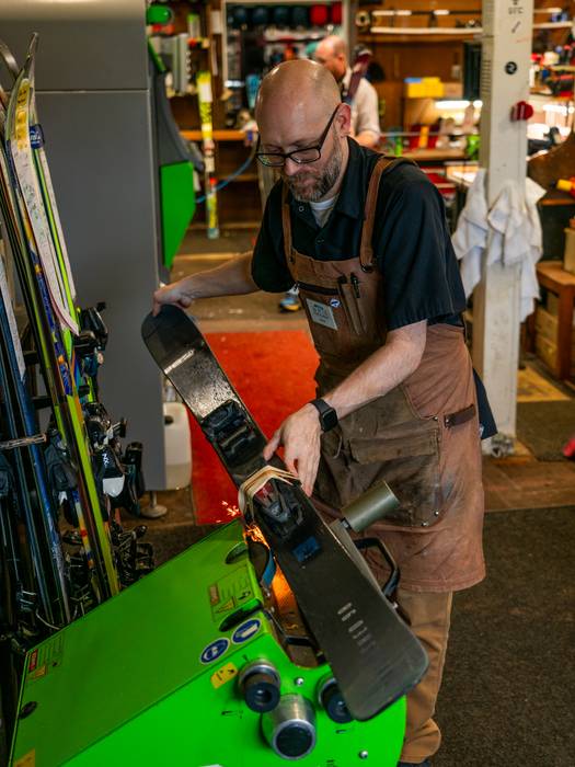 Tune shop employee grinding the edges of a ski