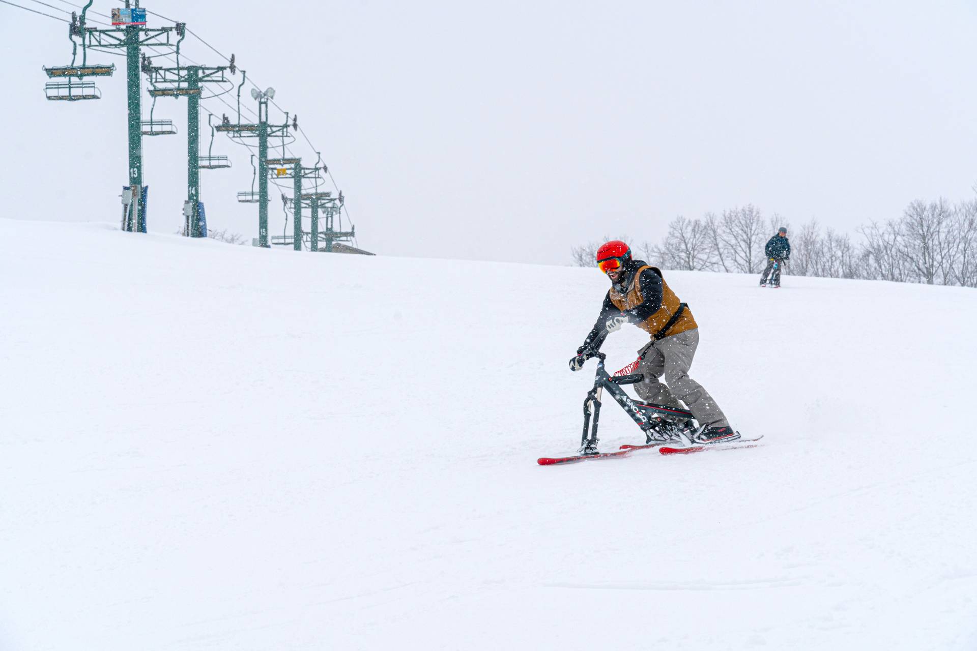 Guy riding SnoGo bike down the ski run