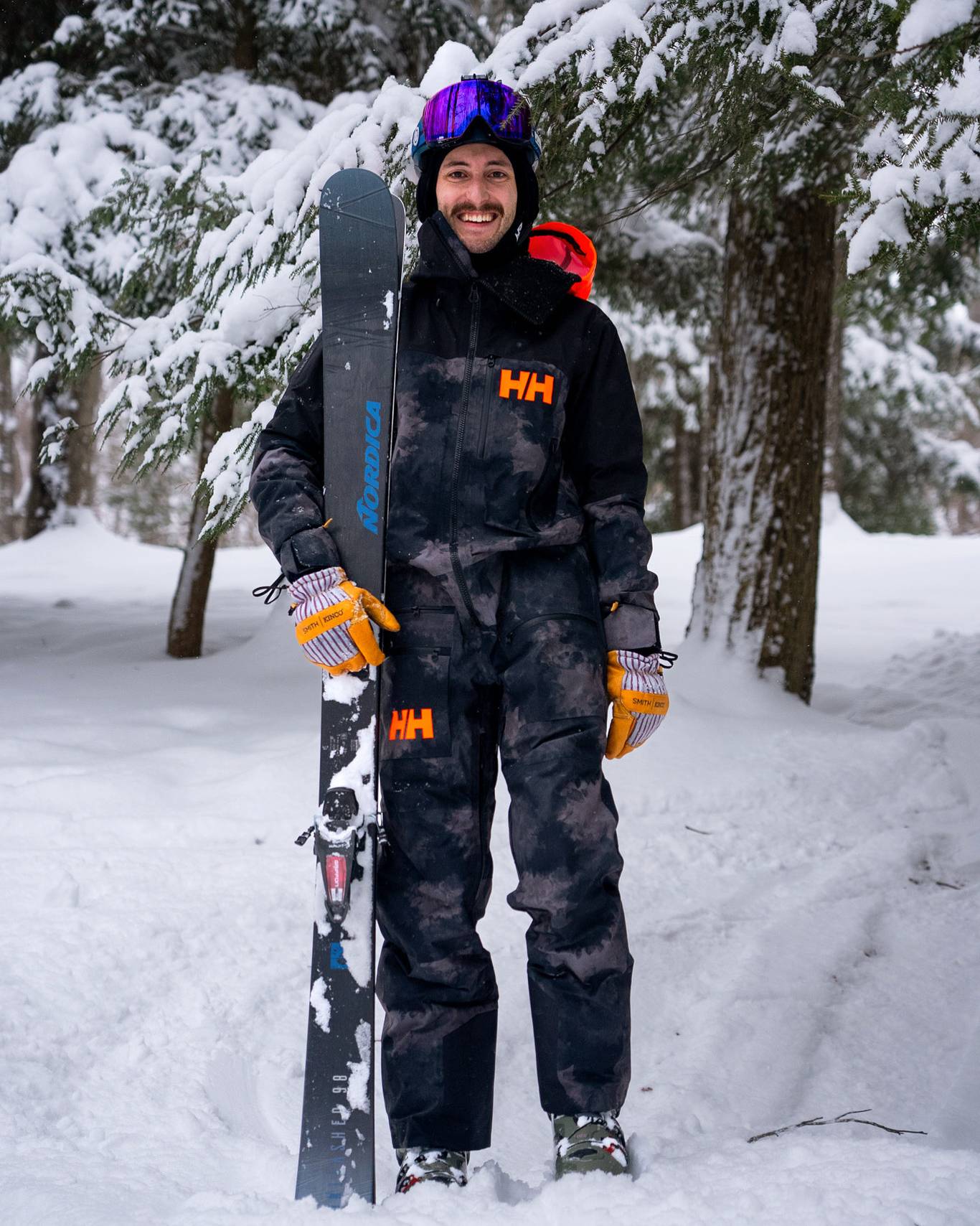 Man holding skis and smiling on the mountain