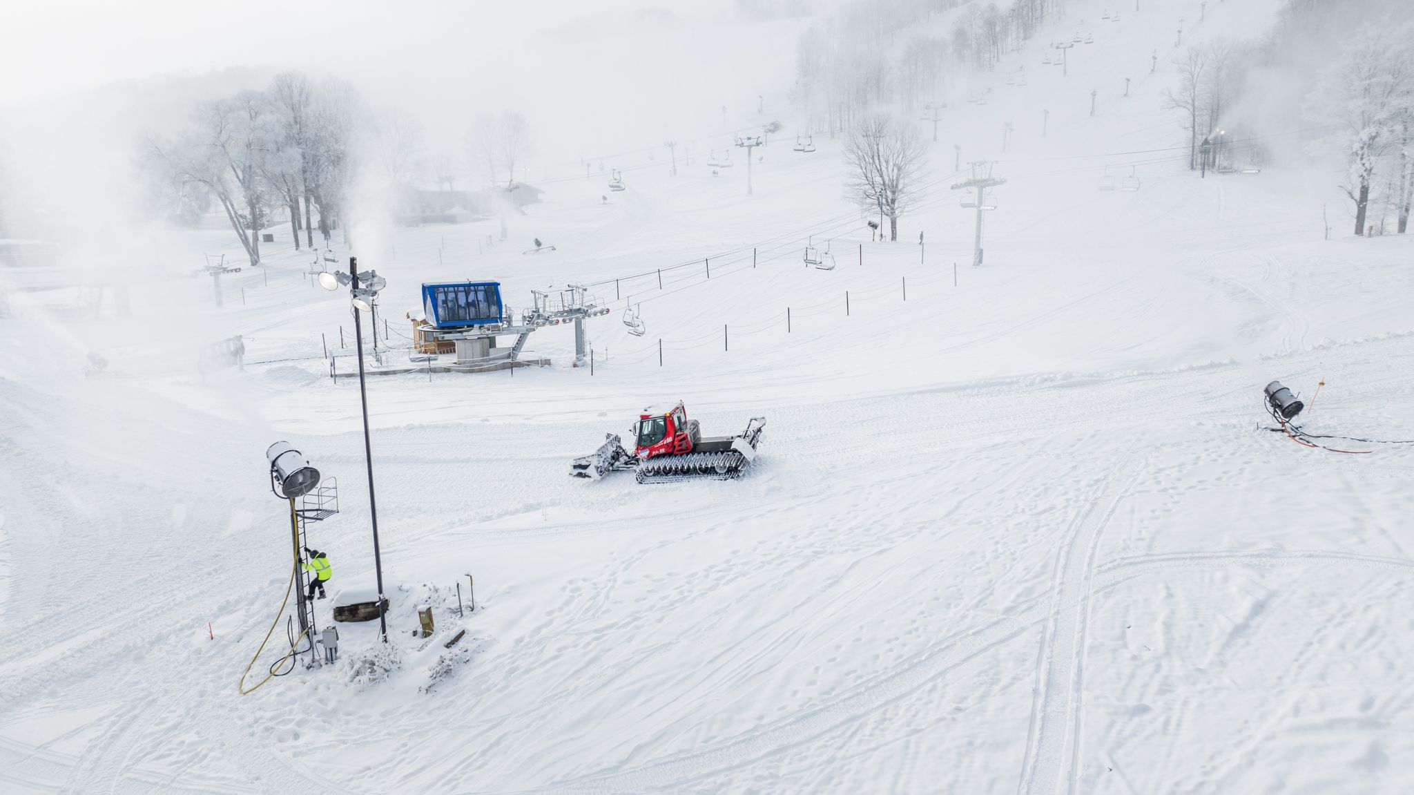 Snowy scene of a snowcat with a snowmaker climbing a snowgun