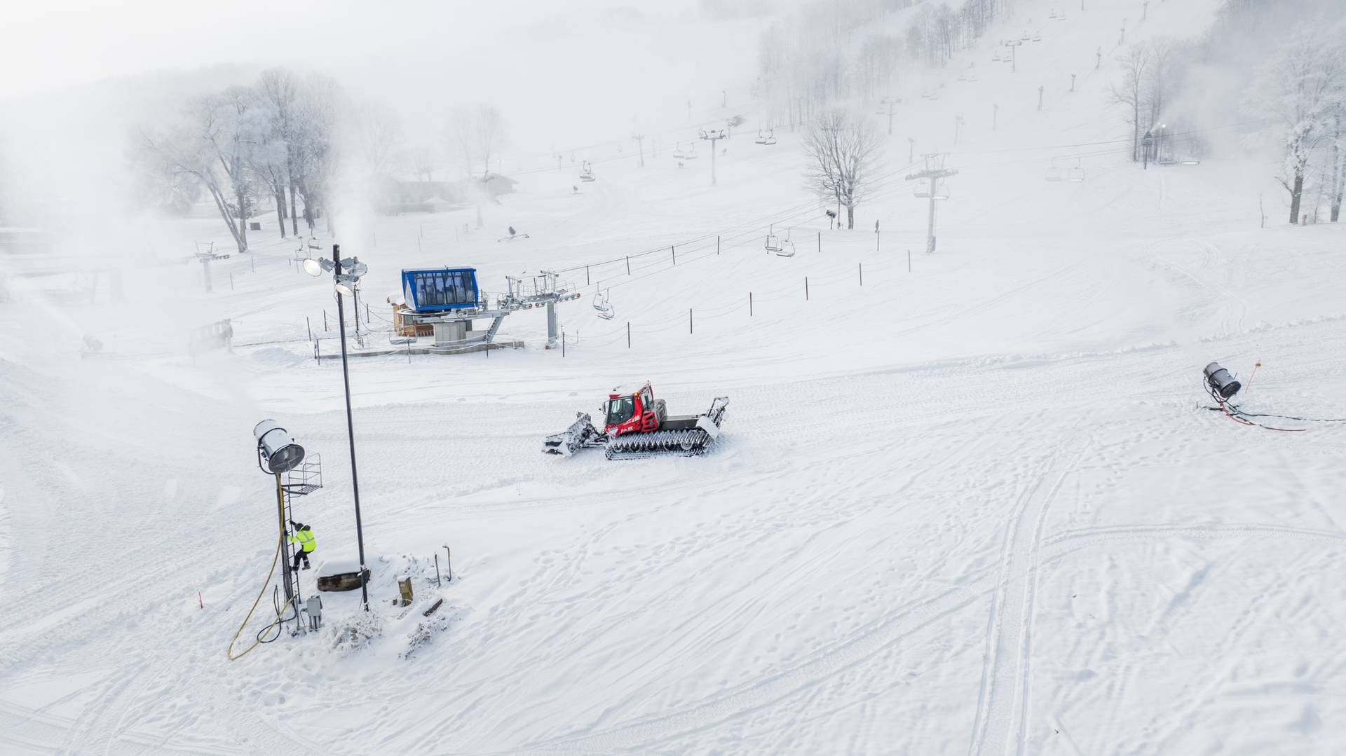 Snowy scene of a snowcat with a snowmaker climbing a snowgun