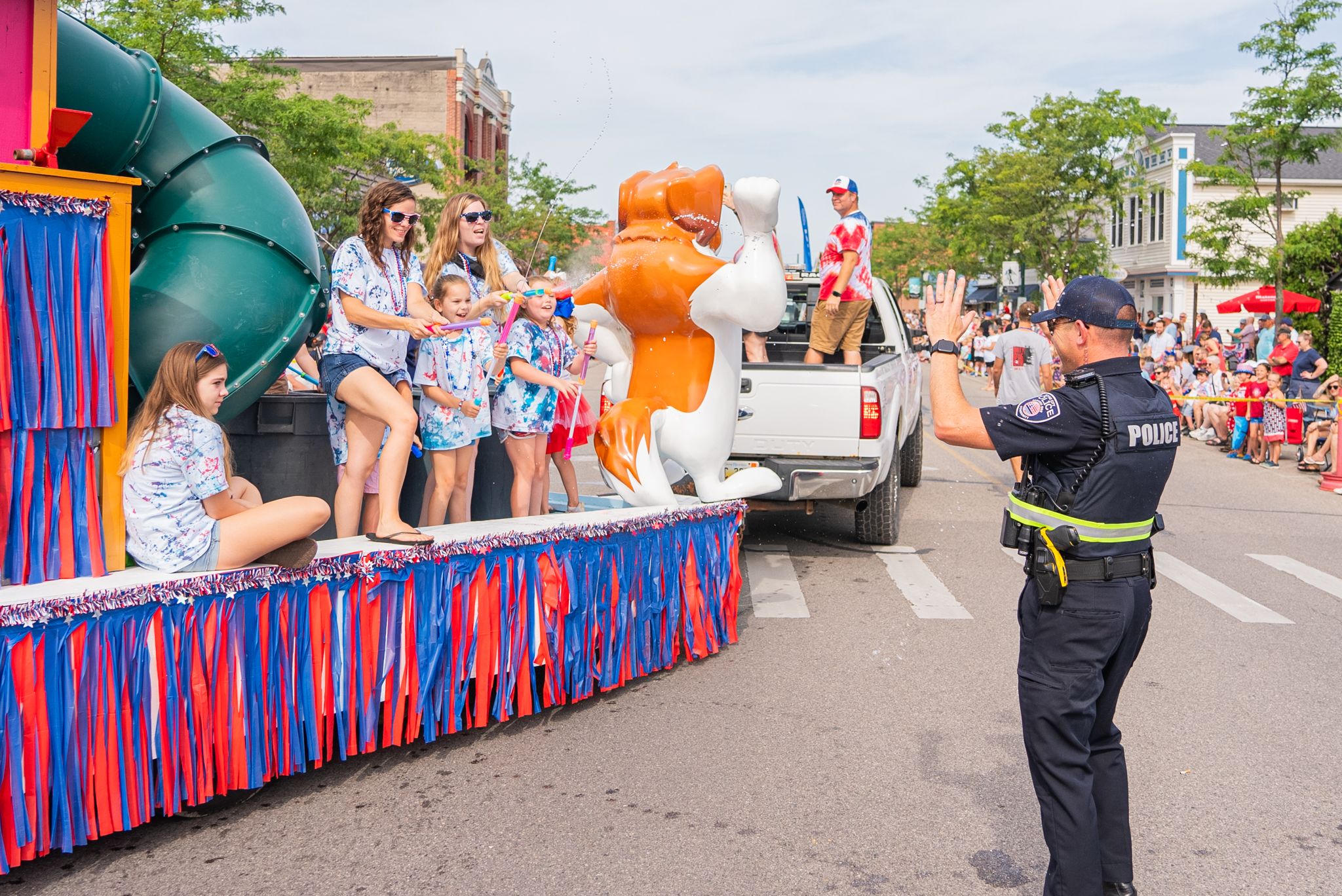 Police officer getting sprayed by kids of parade float