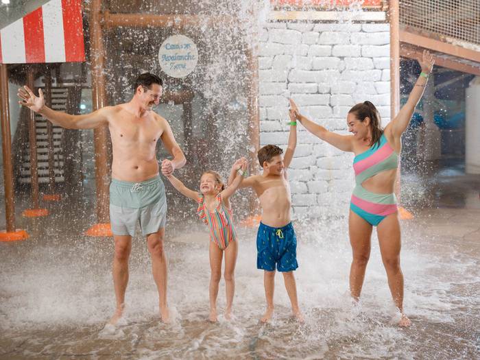 Family standing under splasherhorn water dump