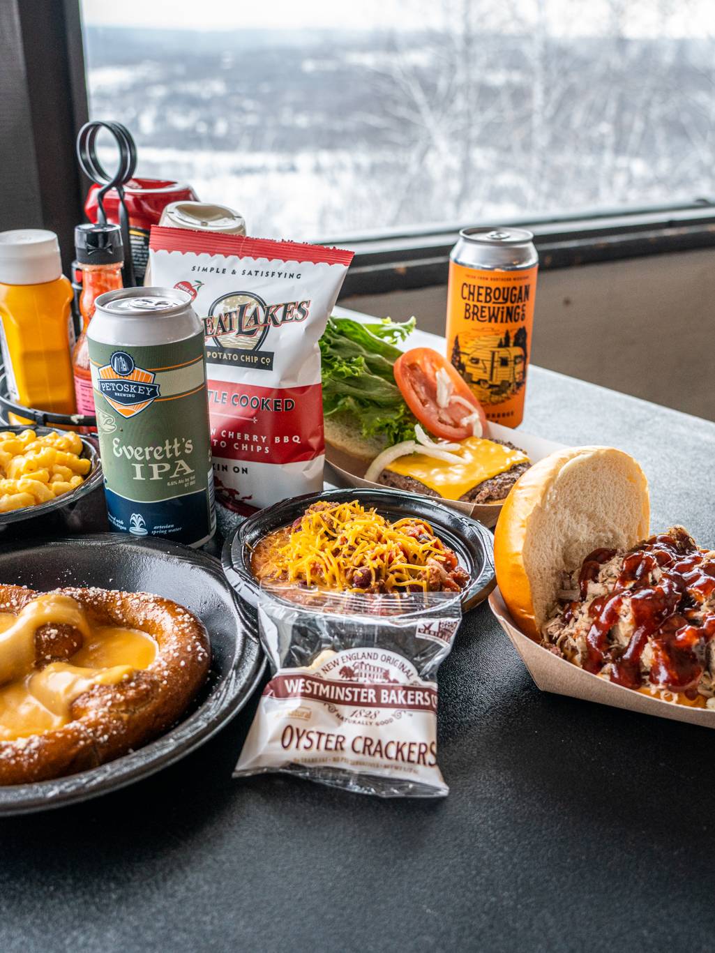 Spread of food at the Eagle's Nest showing sandwiches, chili, mac and cheese, soft pretzels, and beer.