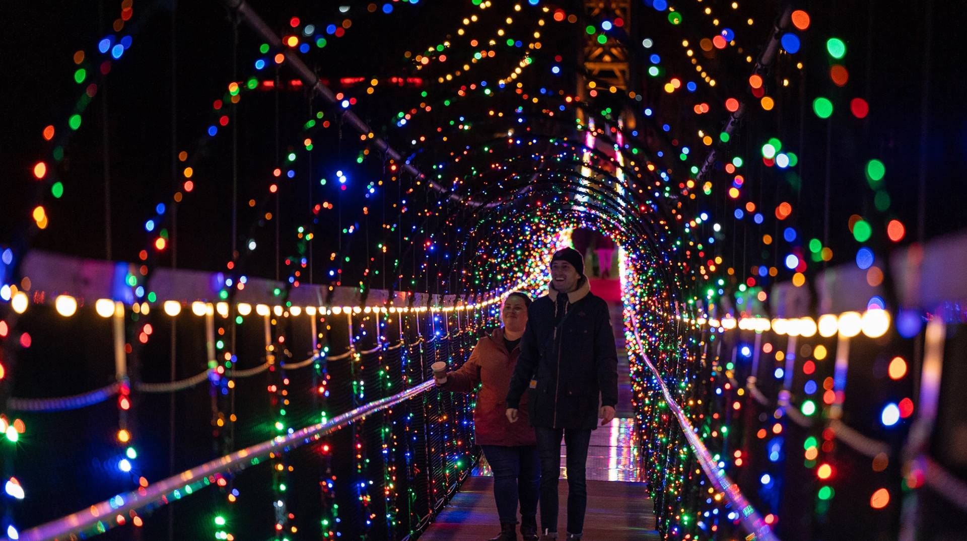 Couple standing on SkyBridge Michigan under holiday lights