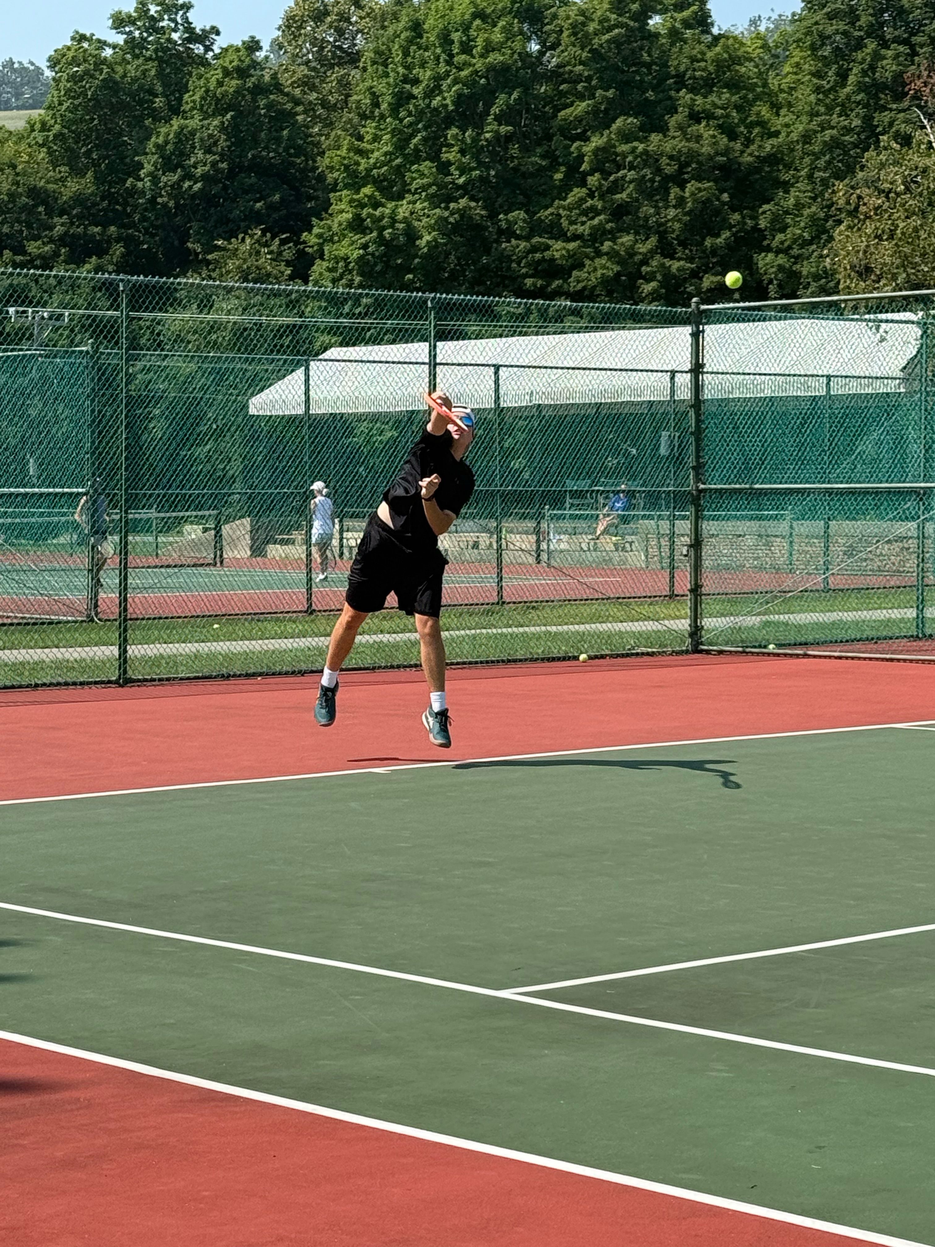 Guy serving a tennis ball