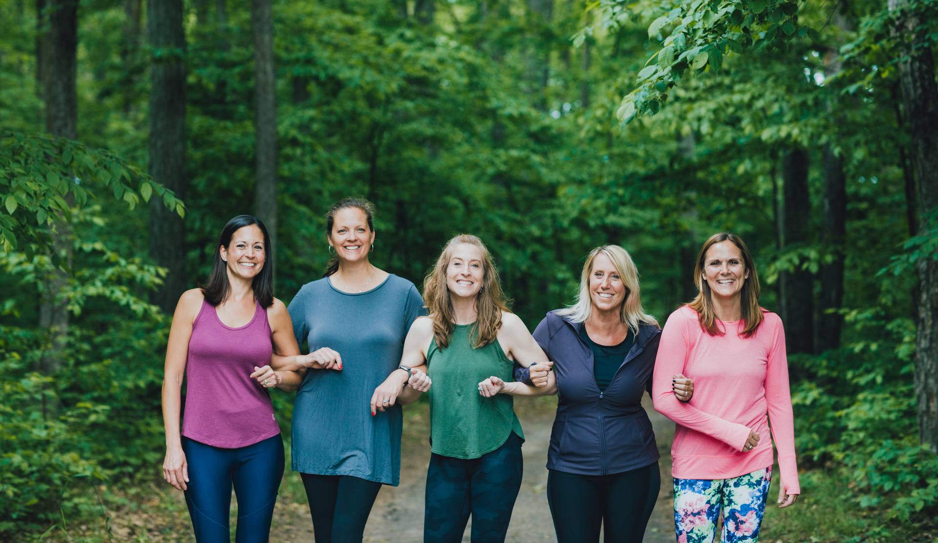 Five ladies locking arms for picture on the paved hiking trail.