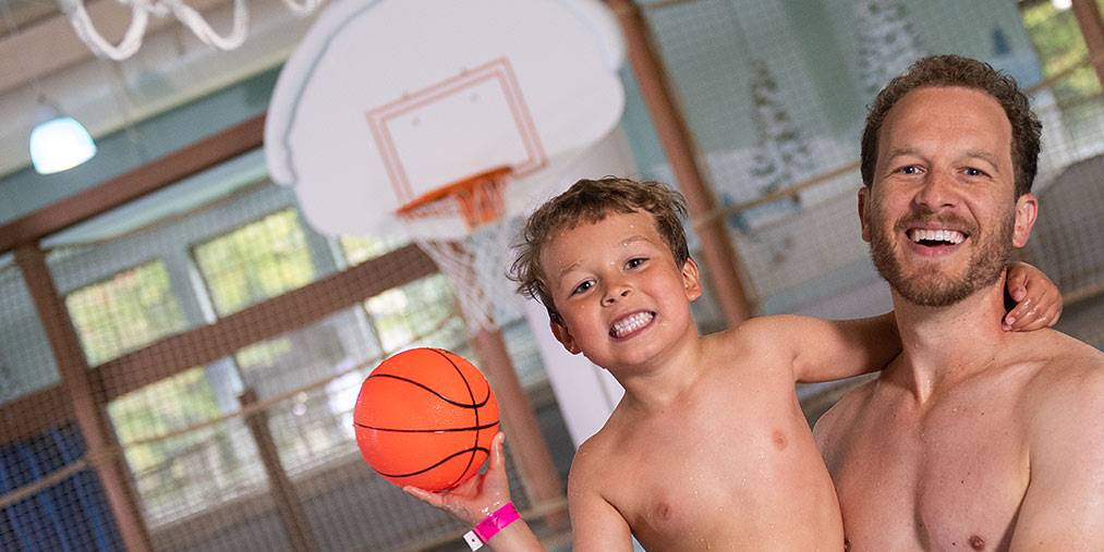 Father and son in pool with basketball