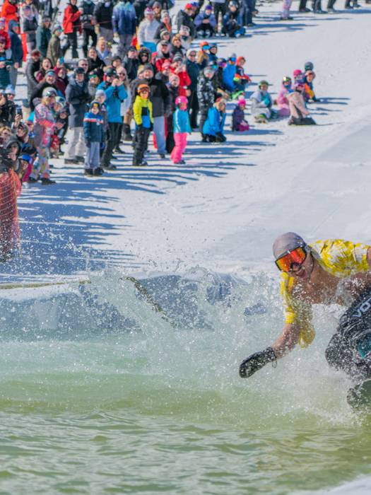 Snowboarder riding across slush cup pool