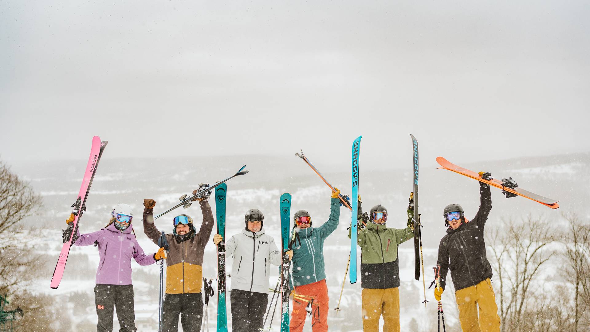group of skiers holding up there skis in excitement