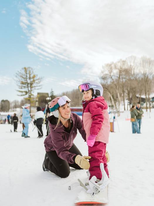 young girl on moms snowboard