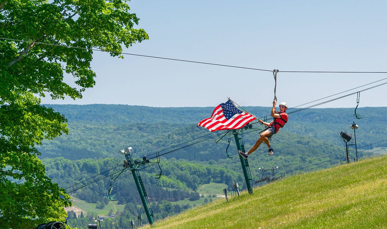 person riding zipline with american flag