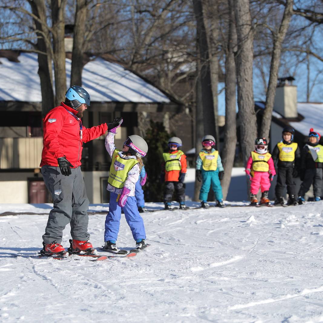 Kid giving instructor a high five with lesson group behind them