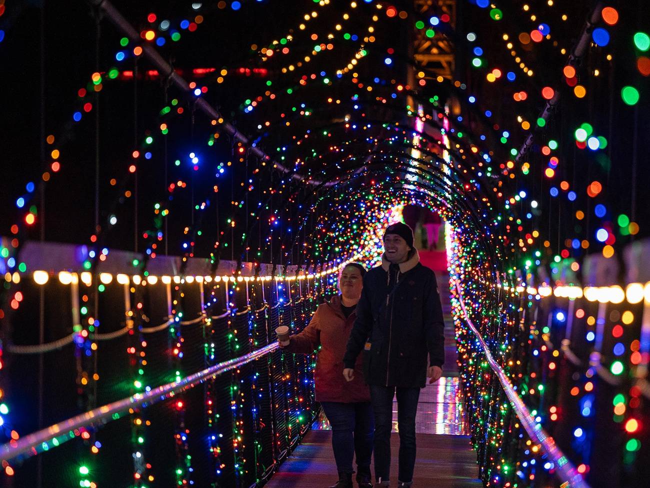 Couple walking over Skybridge Michigan all lit up with lights