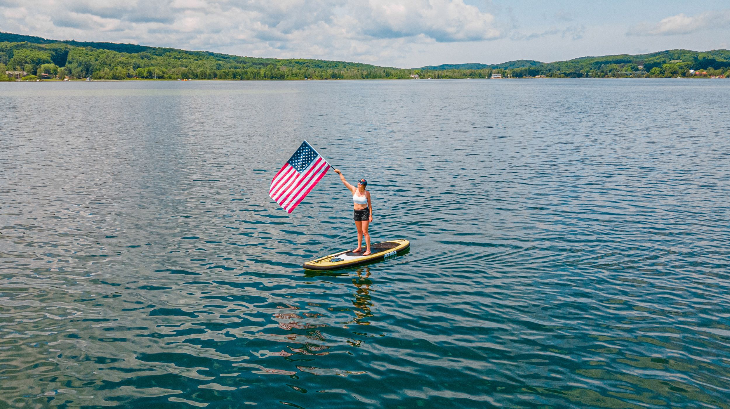 person holding American flag on paddleboard