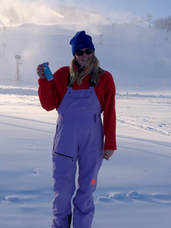 Woman holding red bull in front of ski slope