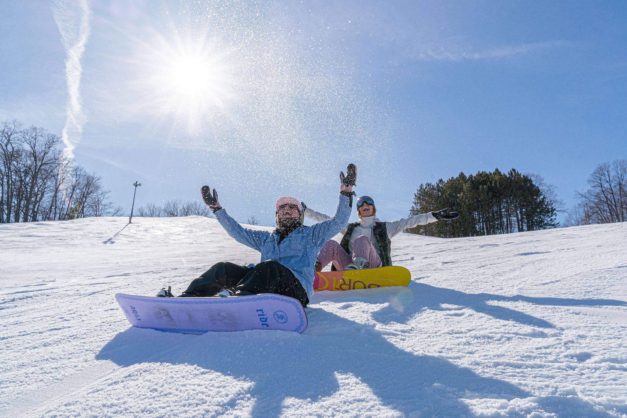 Girl snowboarders sitting on the mountain in the sun