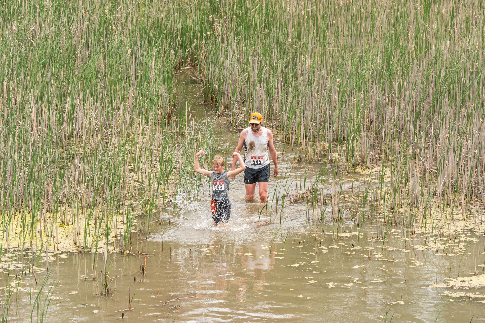 Father and son wading through pond obstacle