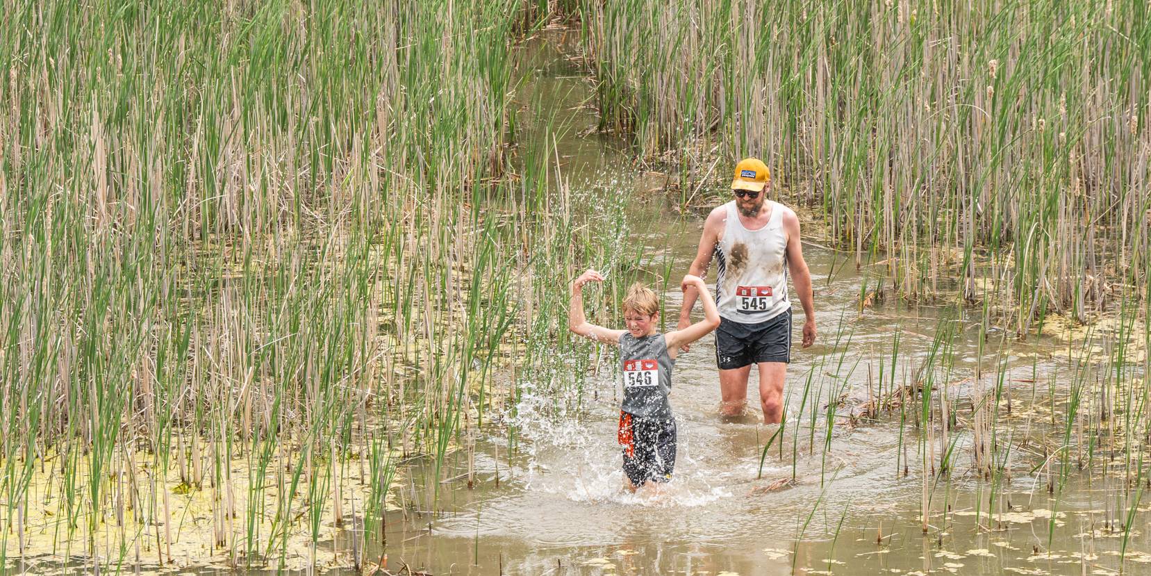 Father and son wading through pond obstacle