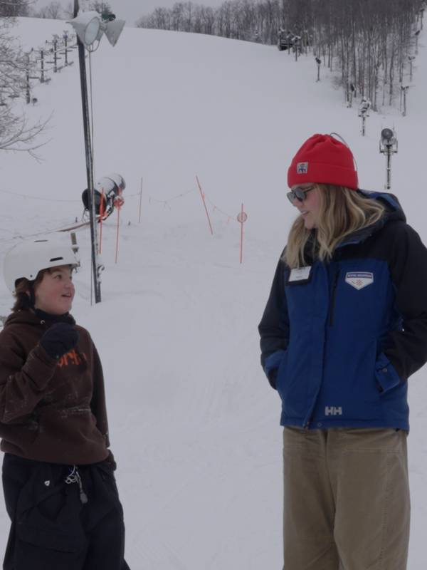 Woman and child standing in front of ski slope