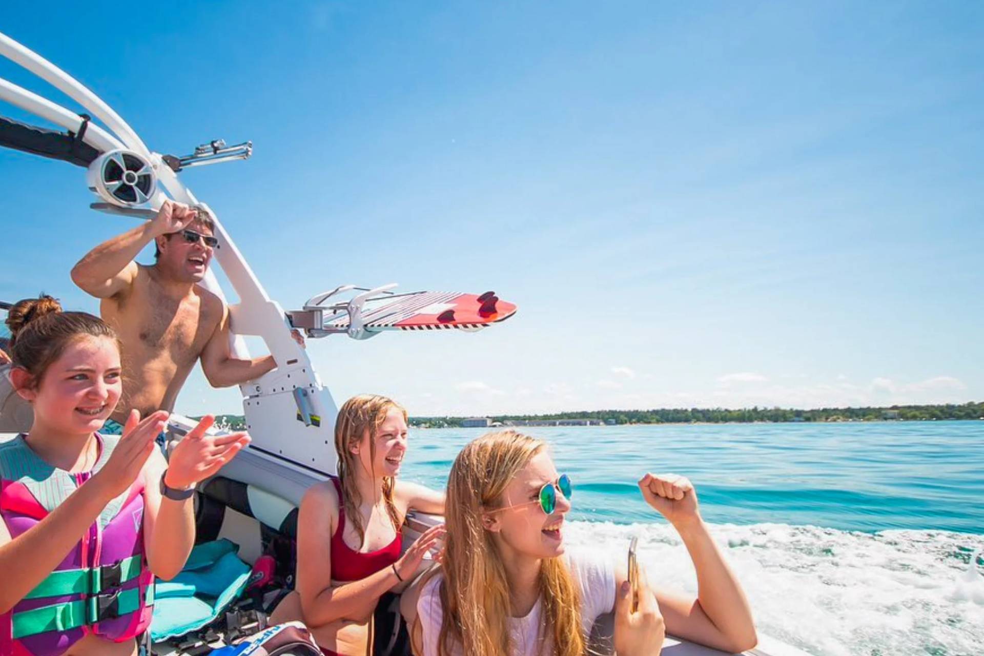 family cheering on wakesurfer from boat