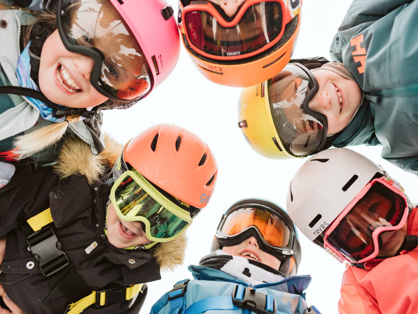 Four kids skier walking at the bottom of the lift with skis on their shoulders.