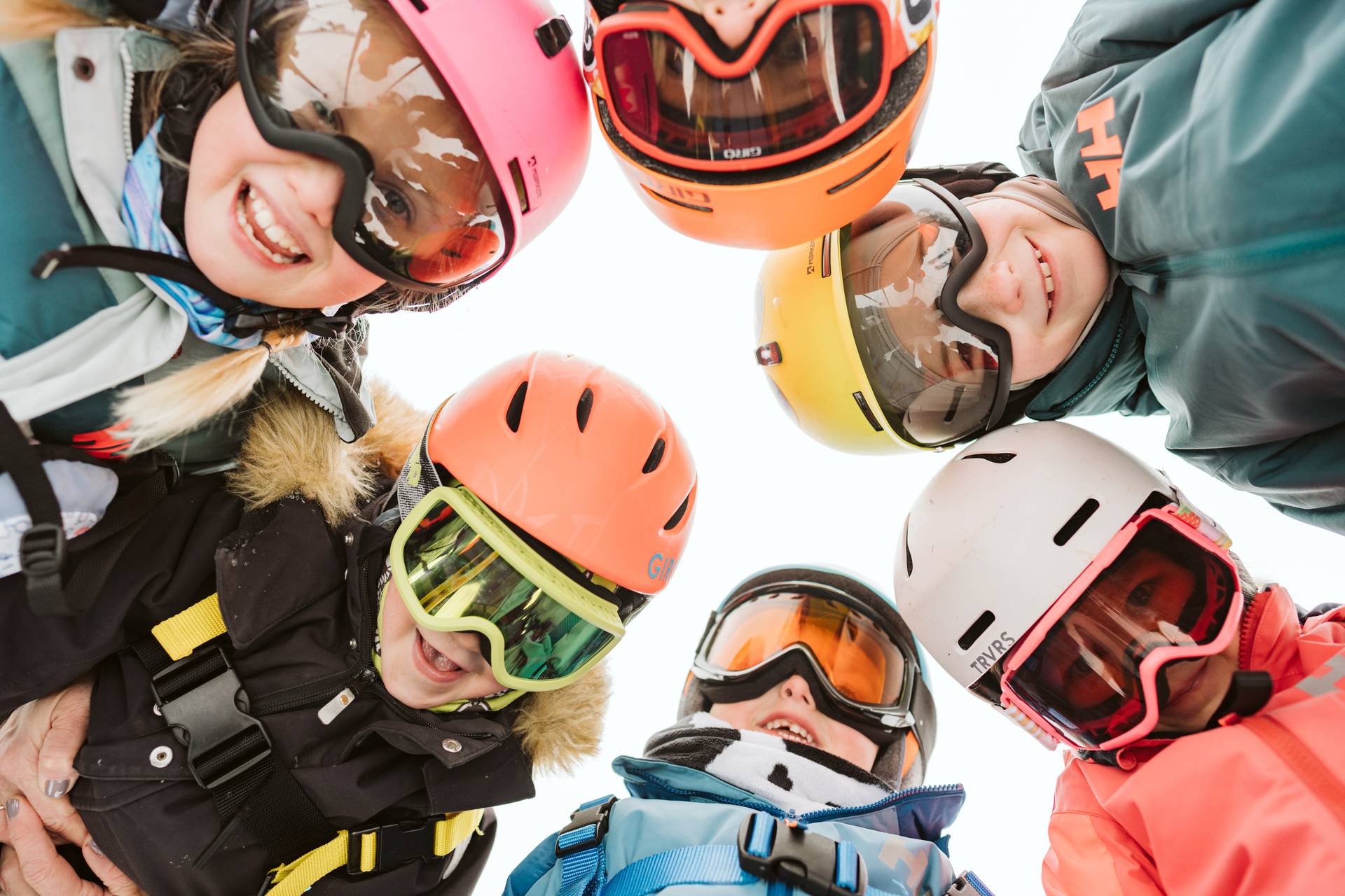 Group of kids carrying skis on the mountain base