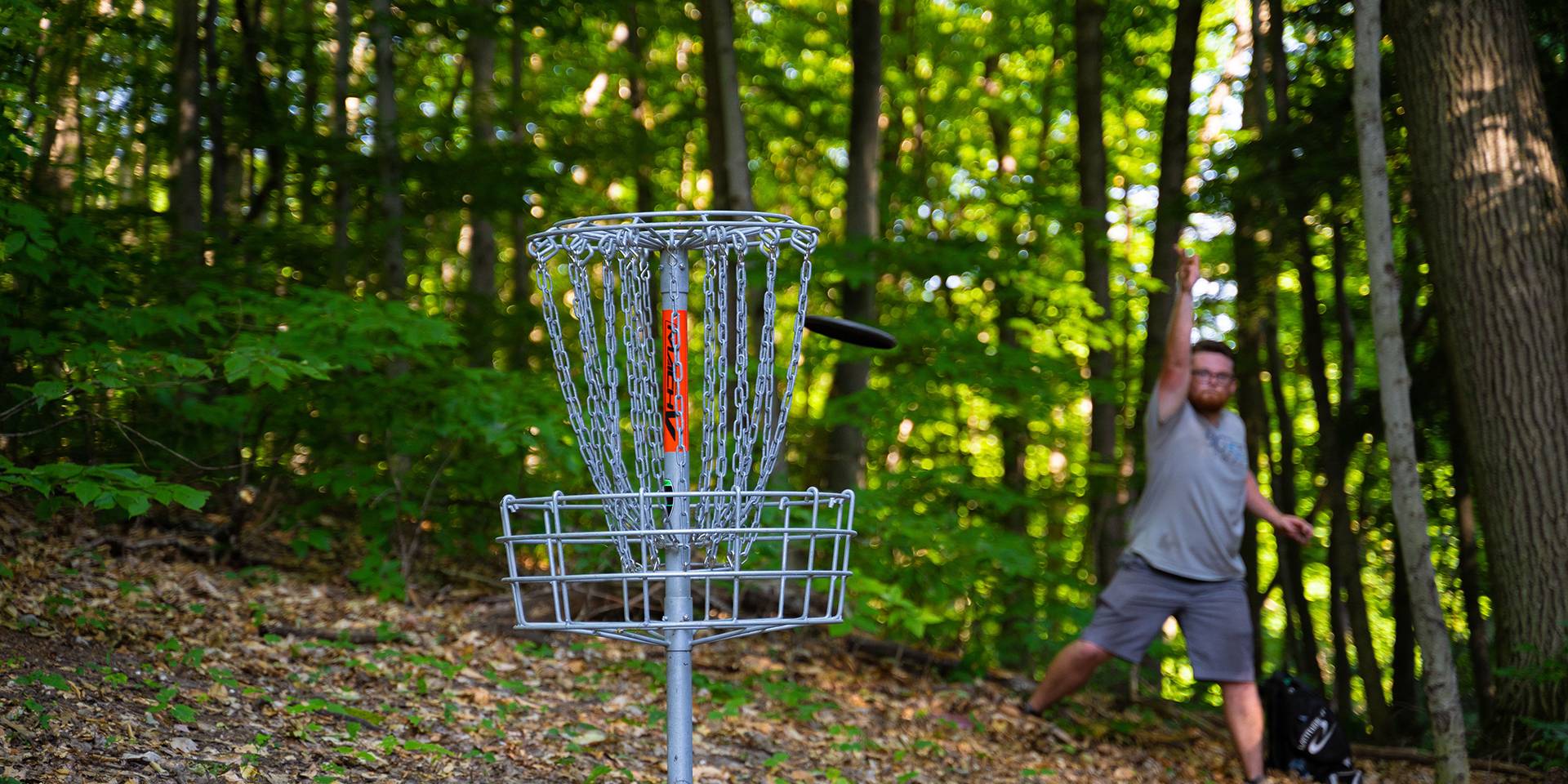 Guy throwing discs when while disc golfing
