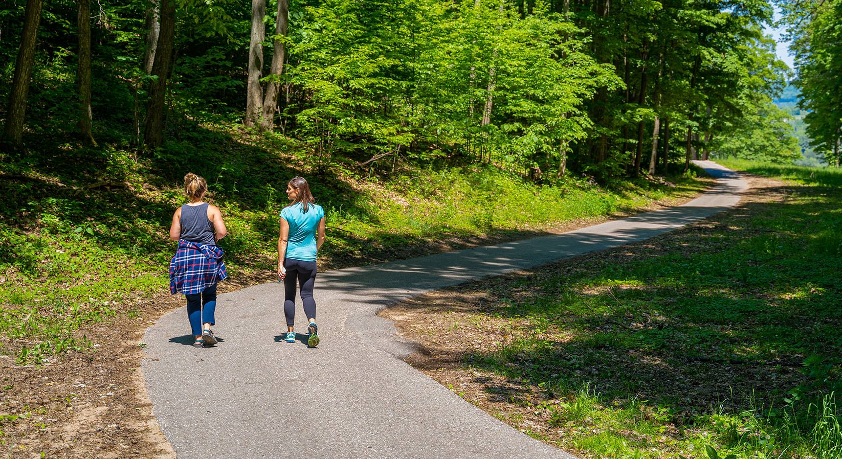 Two ladies walking on paved walking trail.