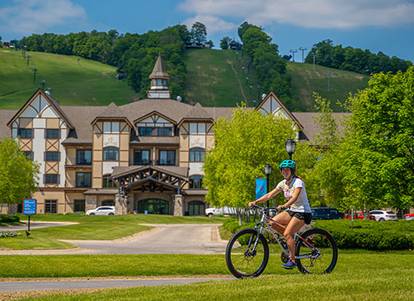 Lady riding her bike on the paved new Boyne Valley bike trail that runs through Boyne Mountain.