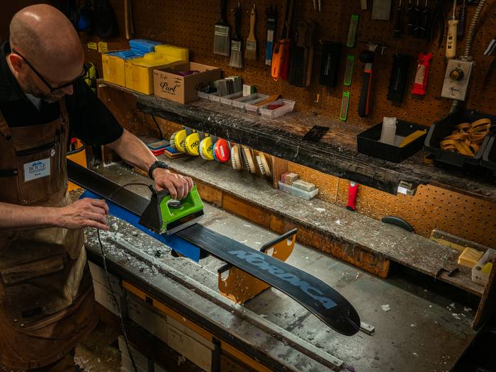 Tune shop employee ironing wax on a ski
