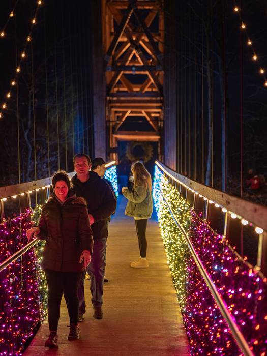 SkyBridge Michigan all lit up at night with people walking on it.