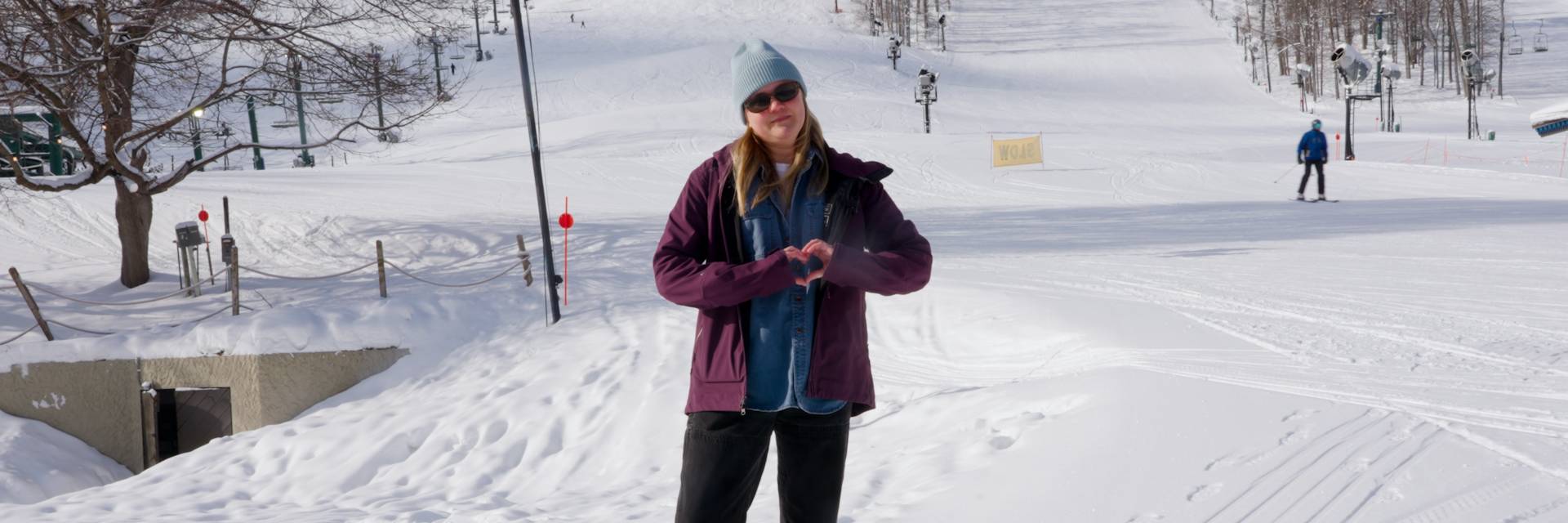 Woman standing at the base of Mountain making a heart with hands