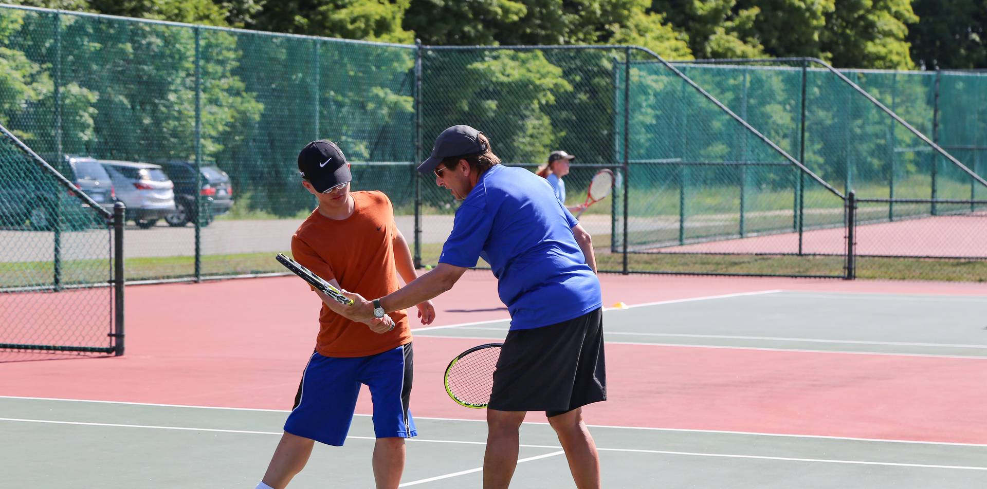 Coach is teaching tennis technique.