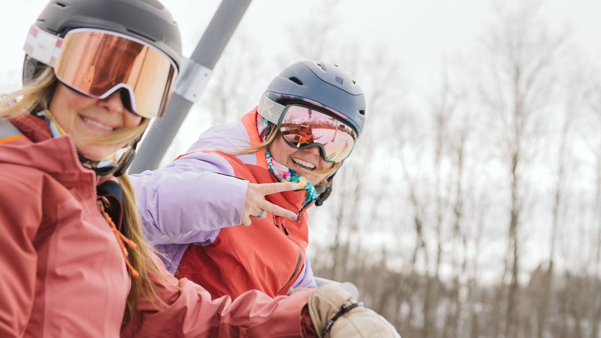 Two ladies on chairlift throwing the piece sign.