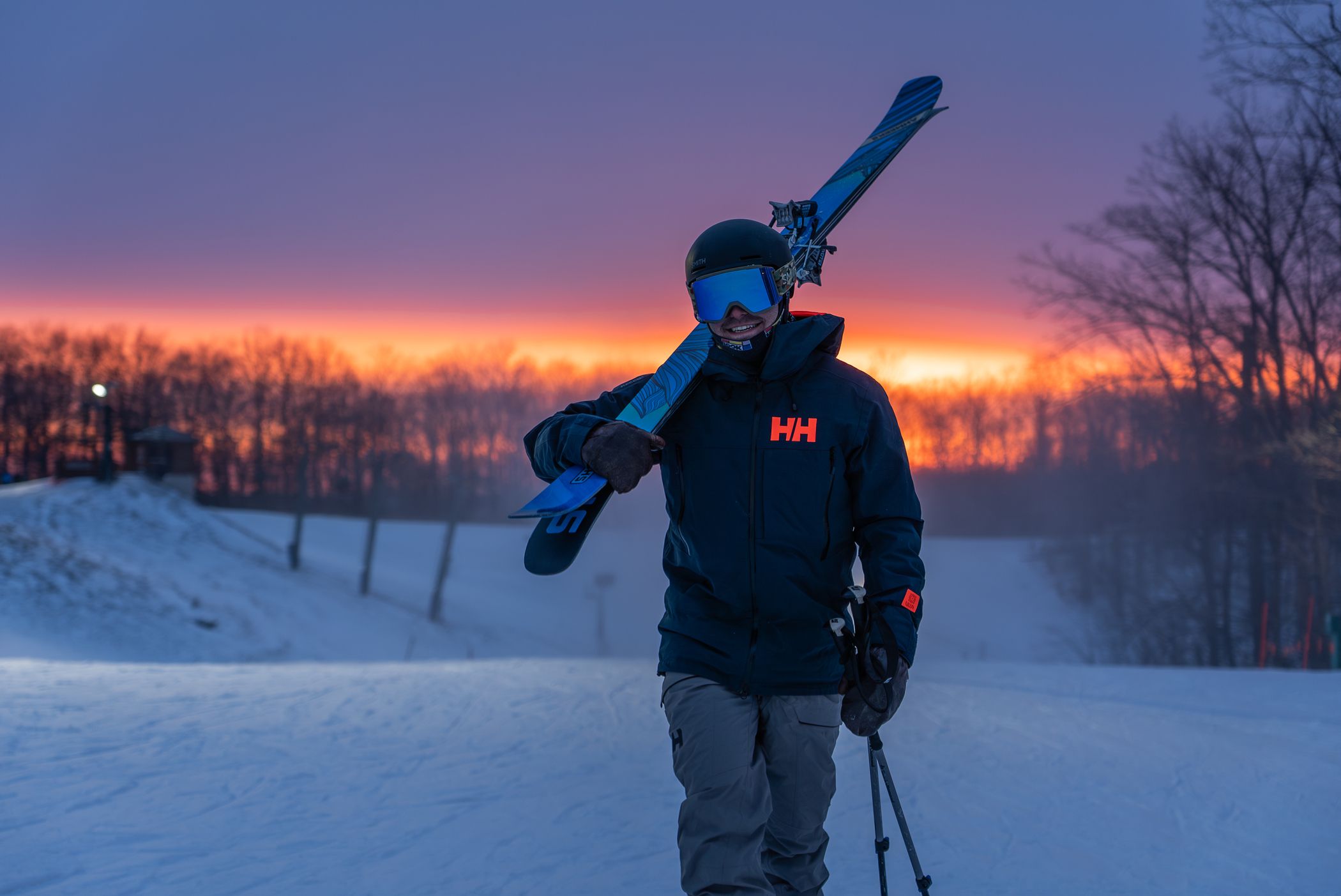 Man carrying skis at night.